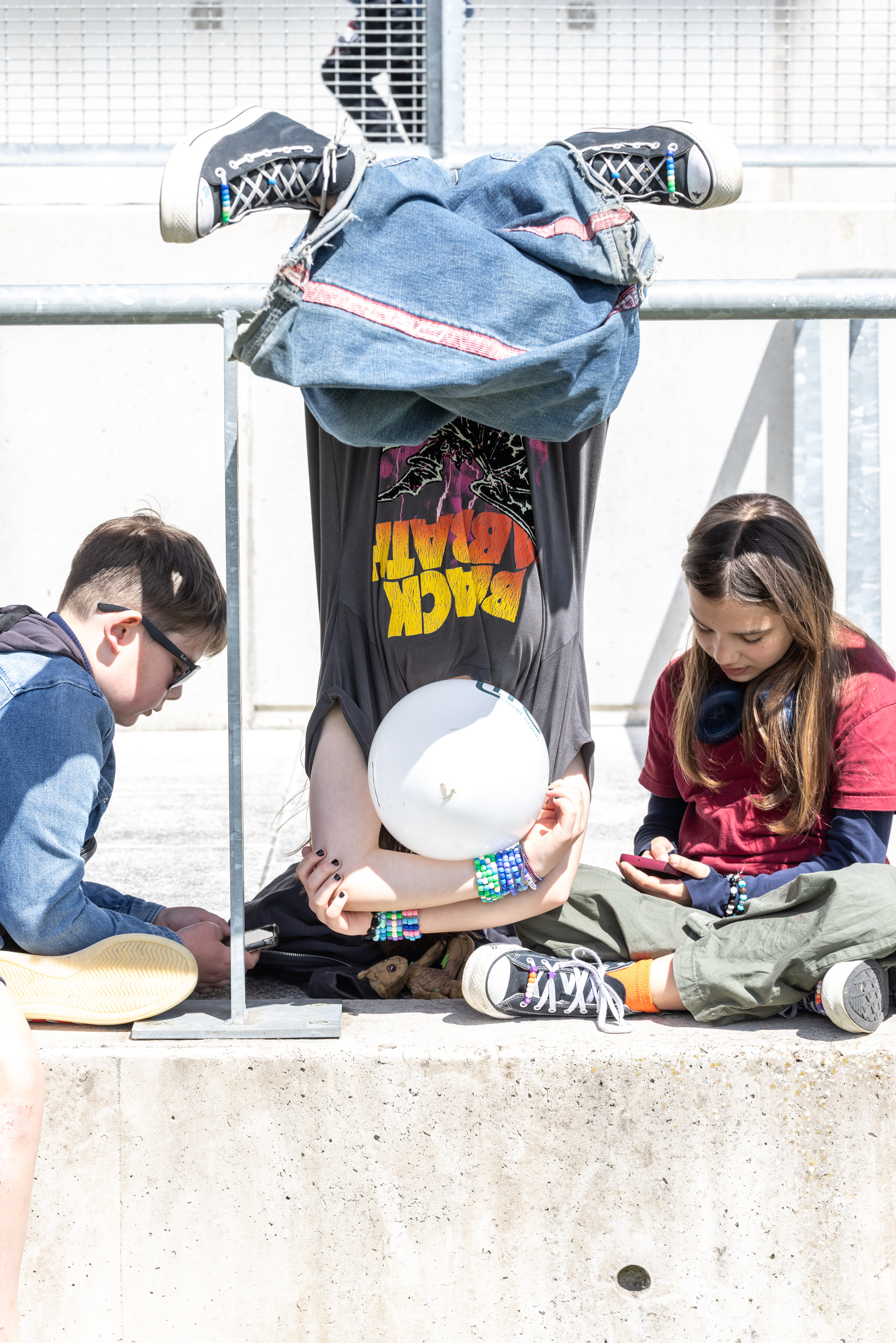 Children sitting in the sun and swinging on railing. 